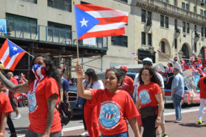 A Young NYDIS Marcher Waves her Flag and Smiles